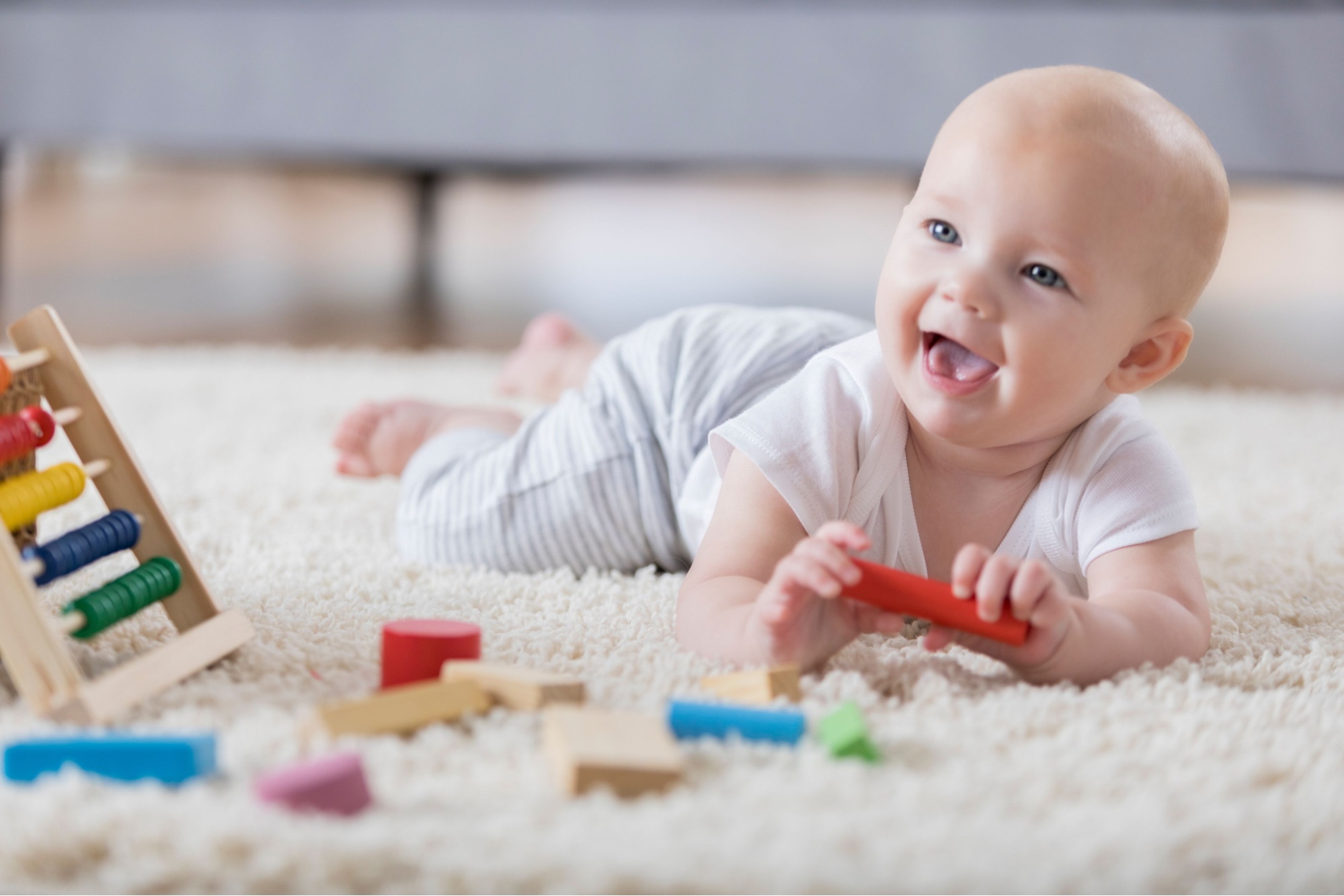 A young baby smiles while playing with toys